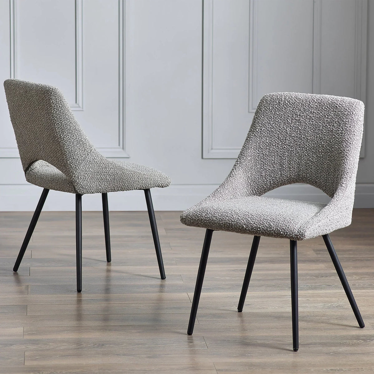 grey boucle dining chairs with black legs on wood floor in modern room
