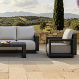 Light grey fabric cushions on black metal frame with slatted black coffee table outdoors