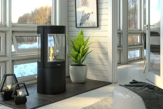 Black freestanding fireplace with glass sides in modern living room near large windows