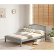 A single bed frame in a light gray finish, styled with cream bedding and a brown patterned throw blanket in a bright, modern bedroom setting with wooden blinds and a potted plant.