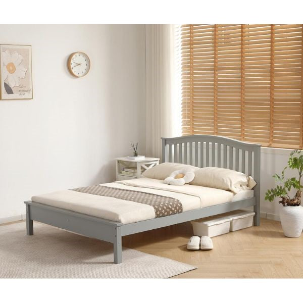 A single bed frame in a light gray finish, styled with cream bedding and a brown patterned throw blanket in a bright, modern bedroom setting with wooden blinds and a potted plant.