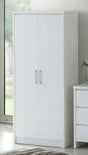 A tall white two-door wardrobe or armoire with slim silver handles, shown in a bright room next to a white three-drawer cabinet.