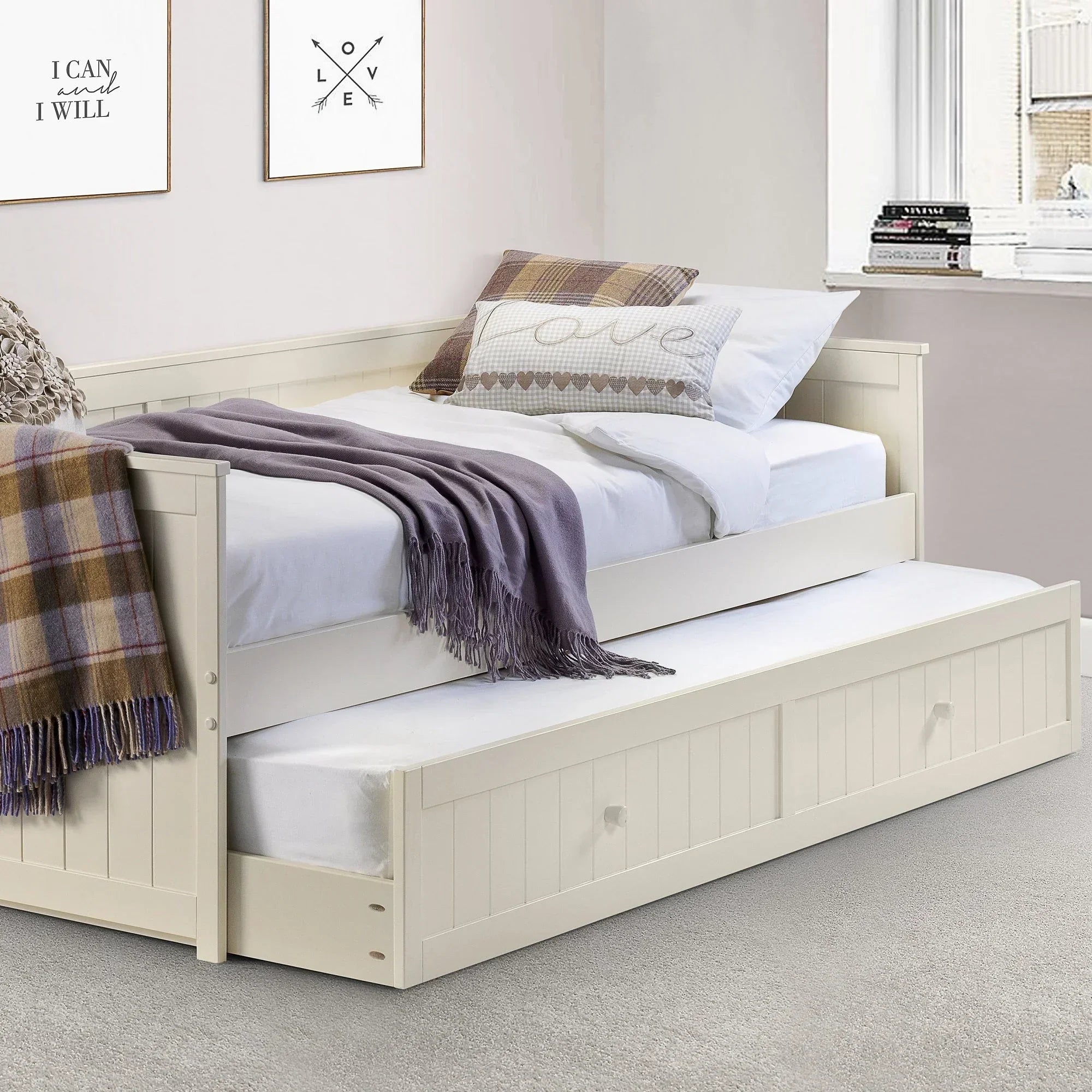 Cream single daybed with pull-out trundle in a modern bedroom, plaid blanket and pillows