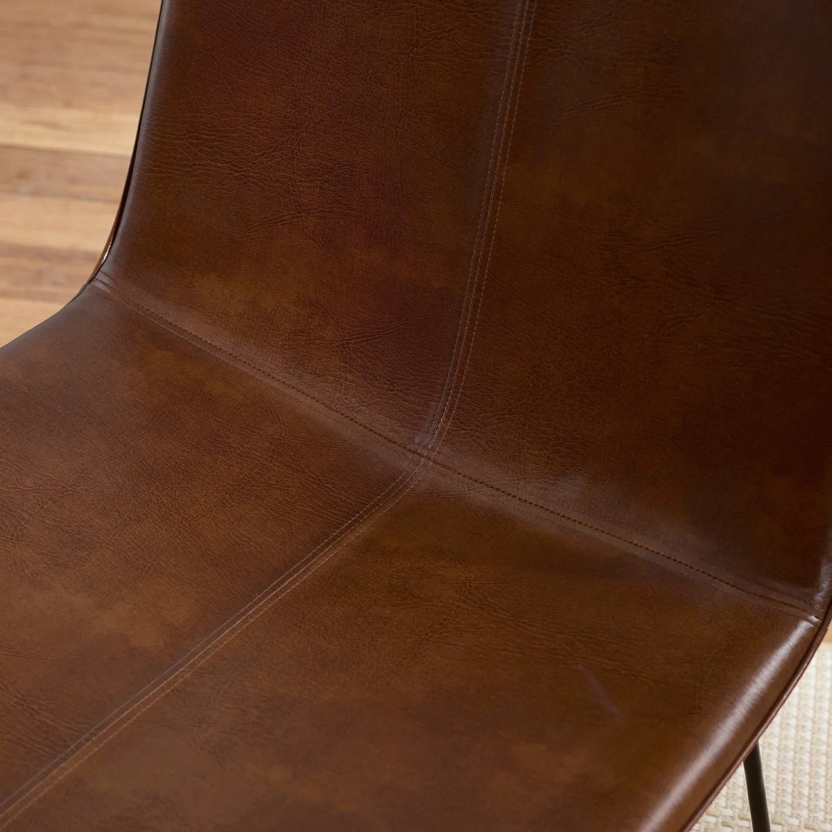 Closeup of brown faux leather dining chair seat with visible stitching detail