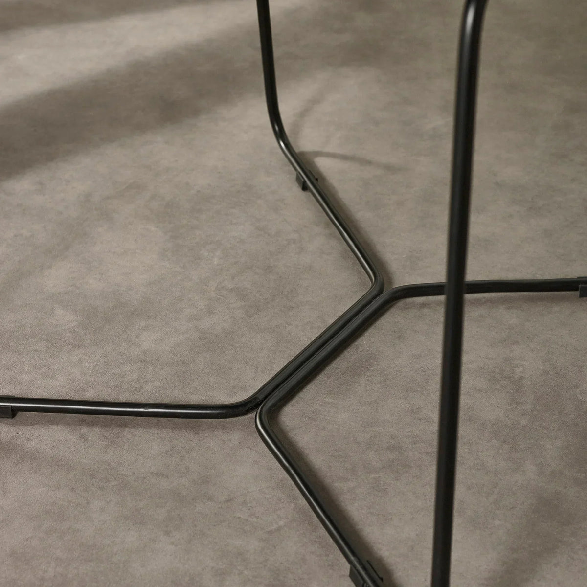 Black metal table legs with modern cross design on grey floor