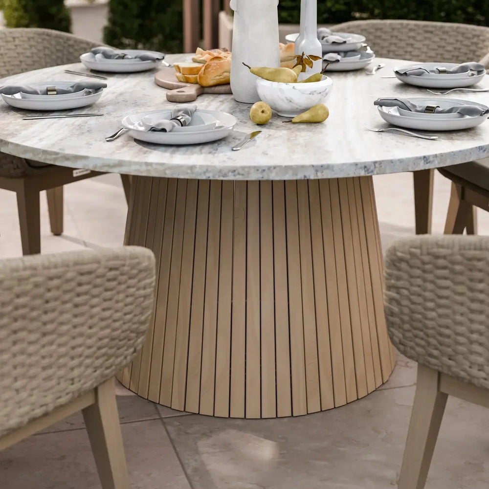 Round marble dining table with light wood base set for outdoor meal, woven chairs around