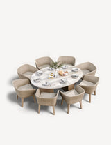 Oval dining table with light wood top and eight wicker armchairs, tableware set for eight