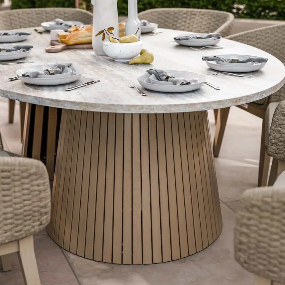 Round marble dining table with slatted wood base set for six with neutral plates and napkins