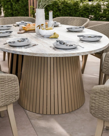 Round marble dining table with slatted wood base set for six with neutral plates and napkins