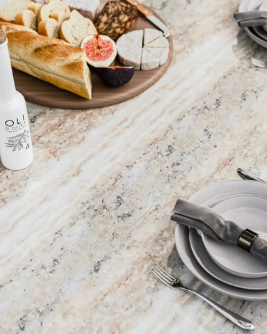 Marble dining table with place setting, bread, cheese, figs, and bottle of olive oil