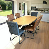 Oak dining table with grey and cognac chairs in modern kitchen dining area