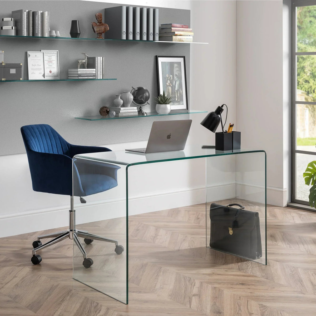 Blue office chair with chrome base next to glass desk in modern home office setting