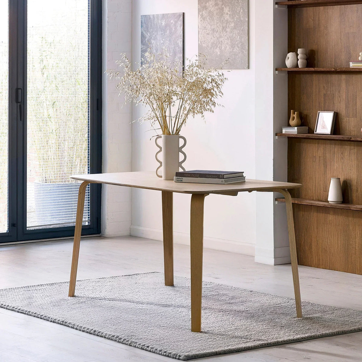Rectangular wood dining table with curved legs on grey rug in modern dining room setting