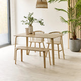 Light wood dining table set with bench and chairs in a modern room with plant decor