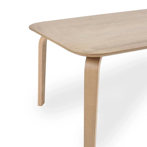 Light wood dining table with curved leg and rounded edge, close-up angle