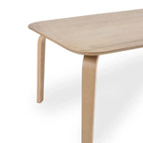 Light wood dining table with curved leg and rounded edge, close-up angle
