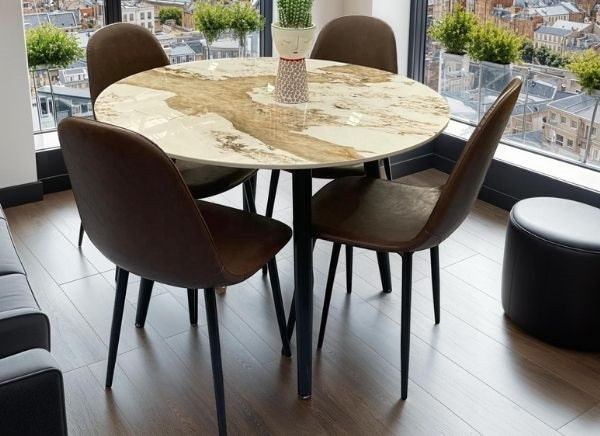 Round dining table with four chairs in a room with large windows.
