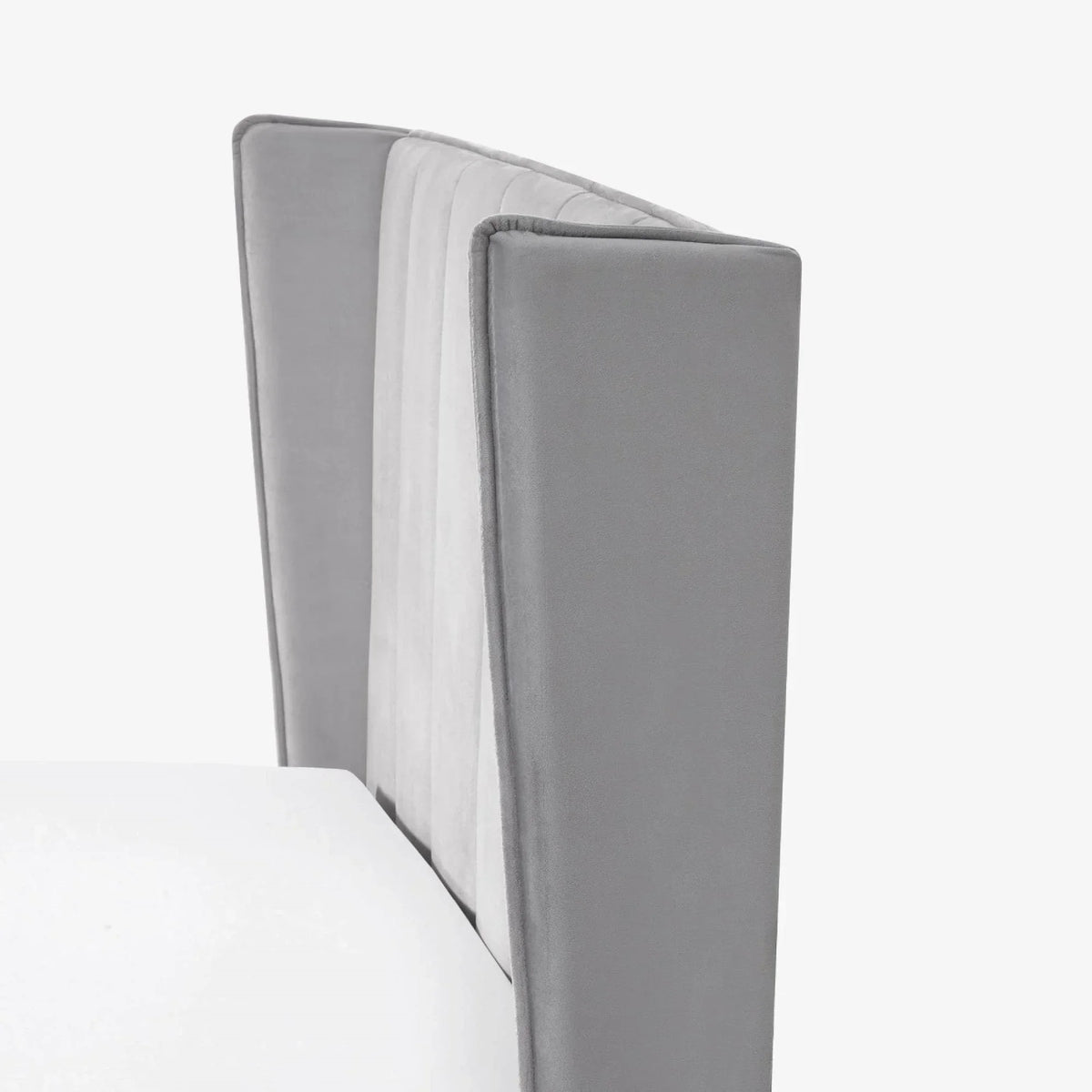 Close-up of grey velvet bed headboard with panelled vertical stitching
