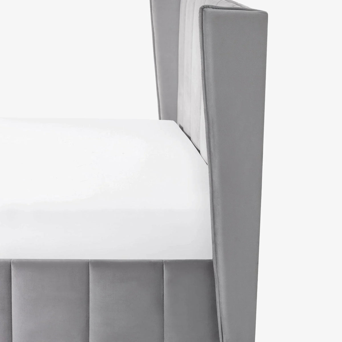 Closeup of grey velvet bed frame corner with white mattress and vertical panel detail