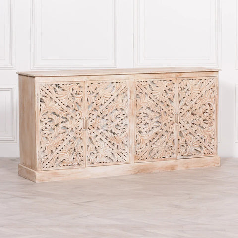 Carved wooden sideboard with ornate floral panels in a whitewashed finish against white wall