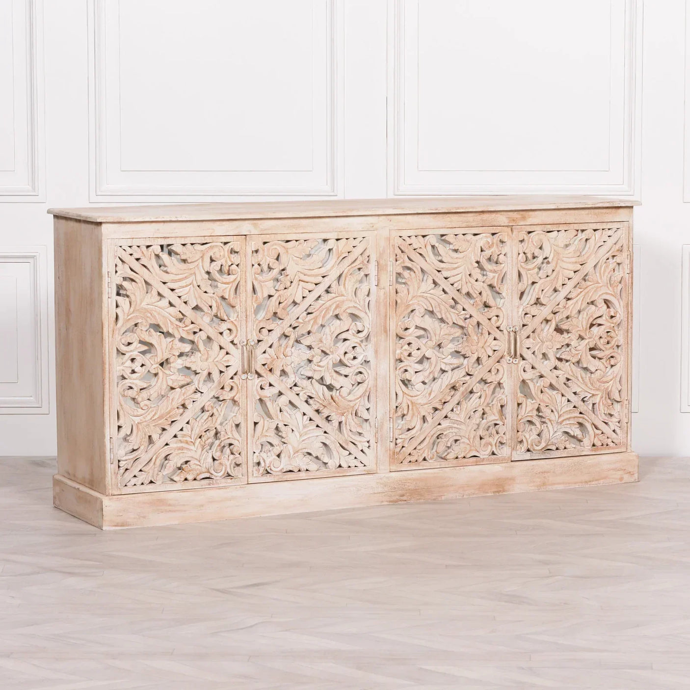 Carved wooden sideboard with ornate floral panels in a whitewashed finish against white wall