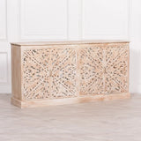 Carved wooden sideboard with ornate floral panels in a whitewashed finish against white wall