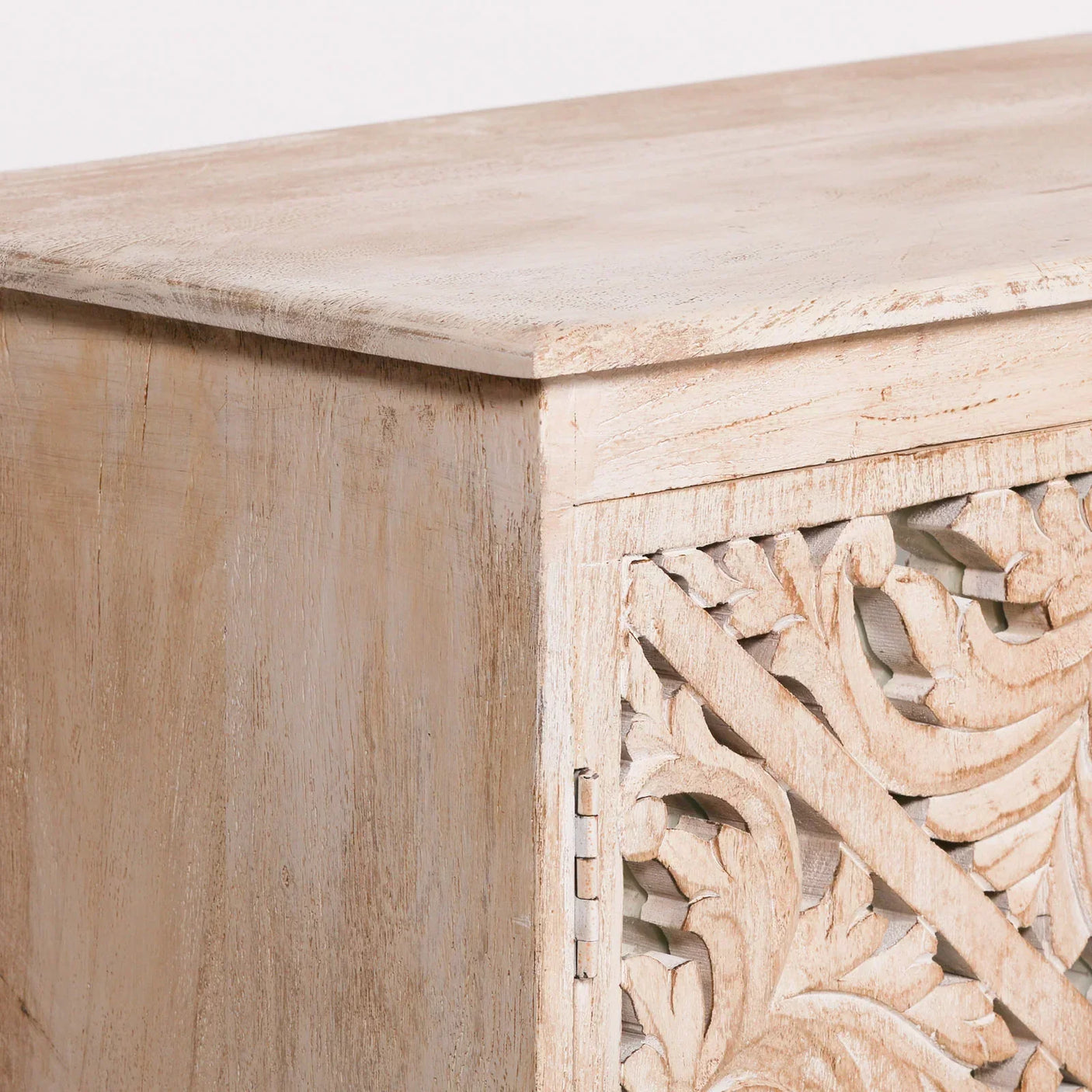 Light wood cabinet corner with carved floral patterned door panel