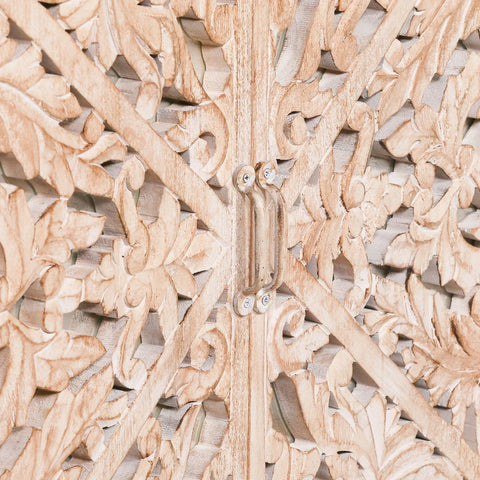 Closeup of carved wood cabinet door with floral detailing and metal handle