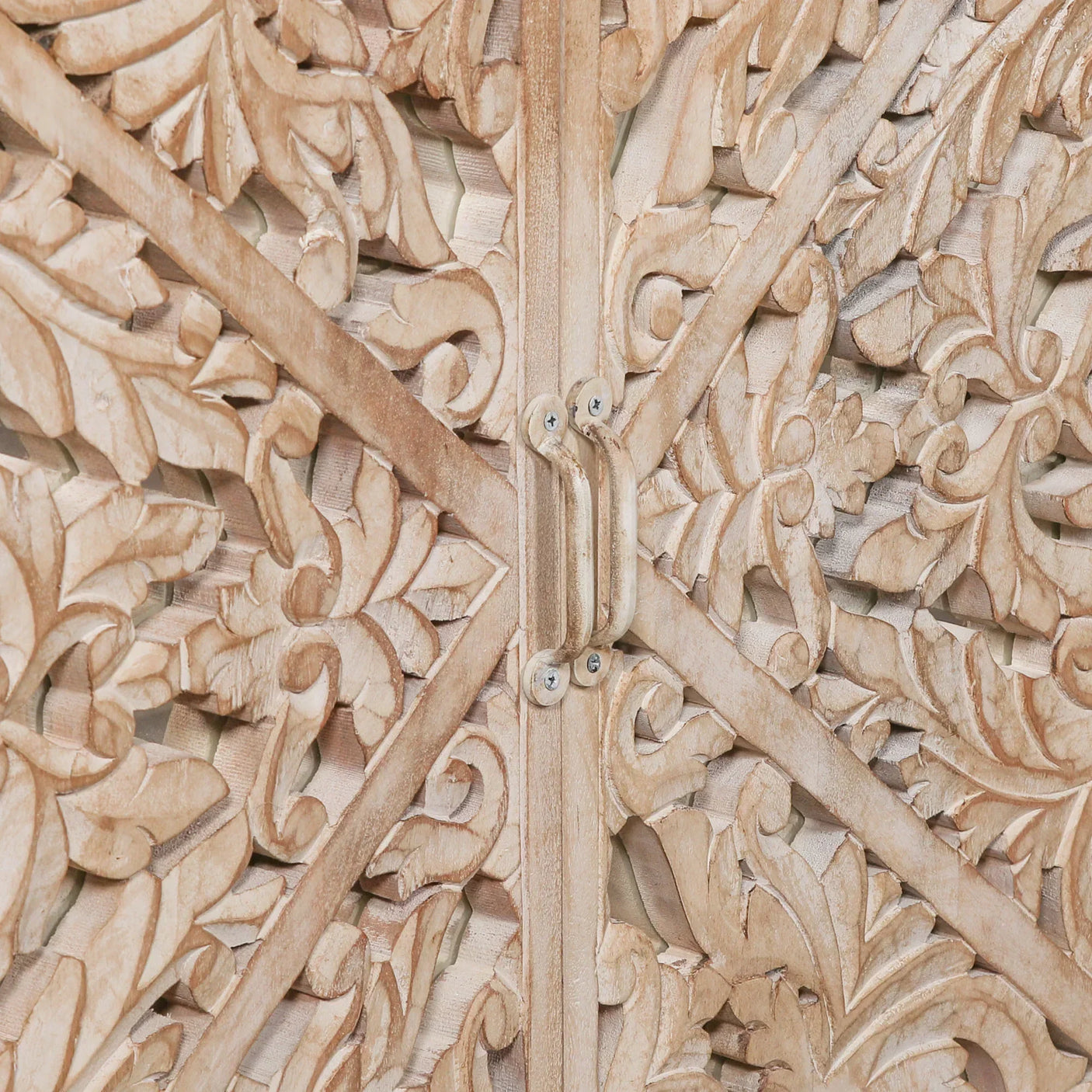 Closeup of carved wood cabinet doors with ornate floral detailing and metal handle