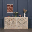 Carved wood sideboard with floral pattern, rustic finish, decorated with vases and flowers