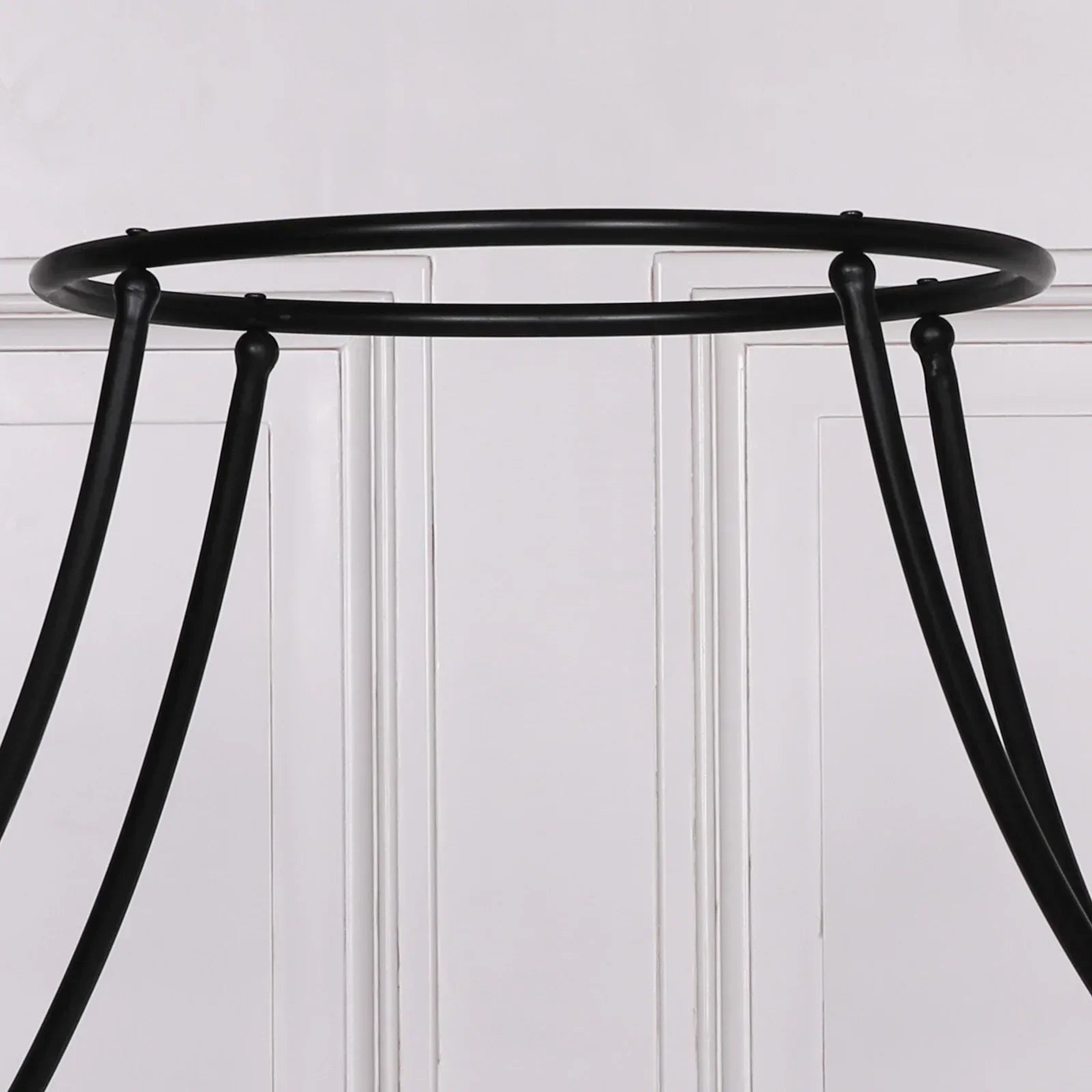 Black metal table base with curved legs against white paneled wall