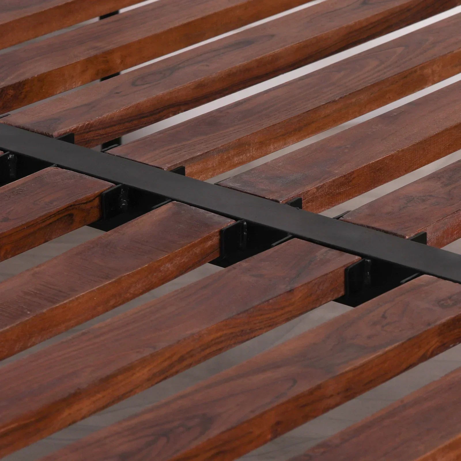 Wooden bed frame slats with metal support bar in close-up detail