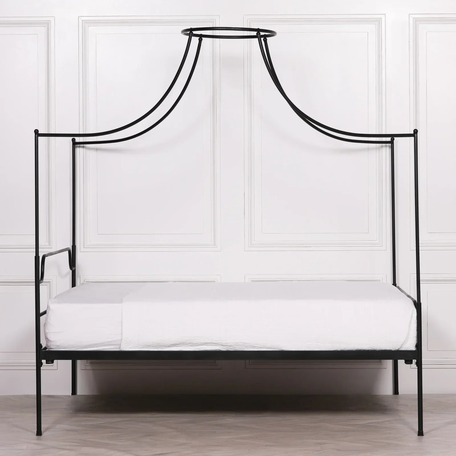 Black metal canopy bed frame with minimalist design and white bedding in modern room