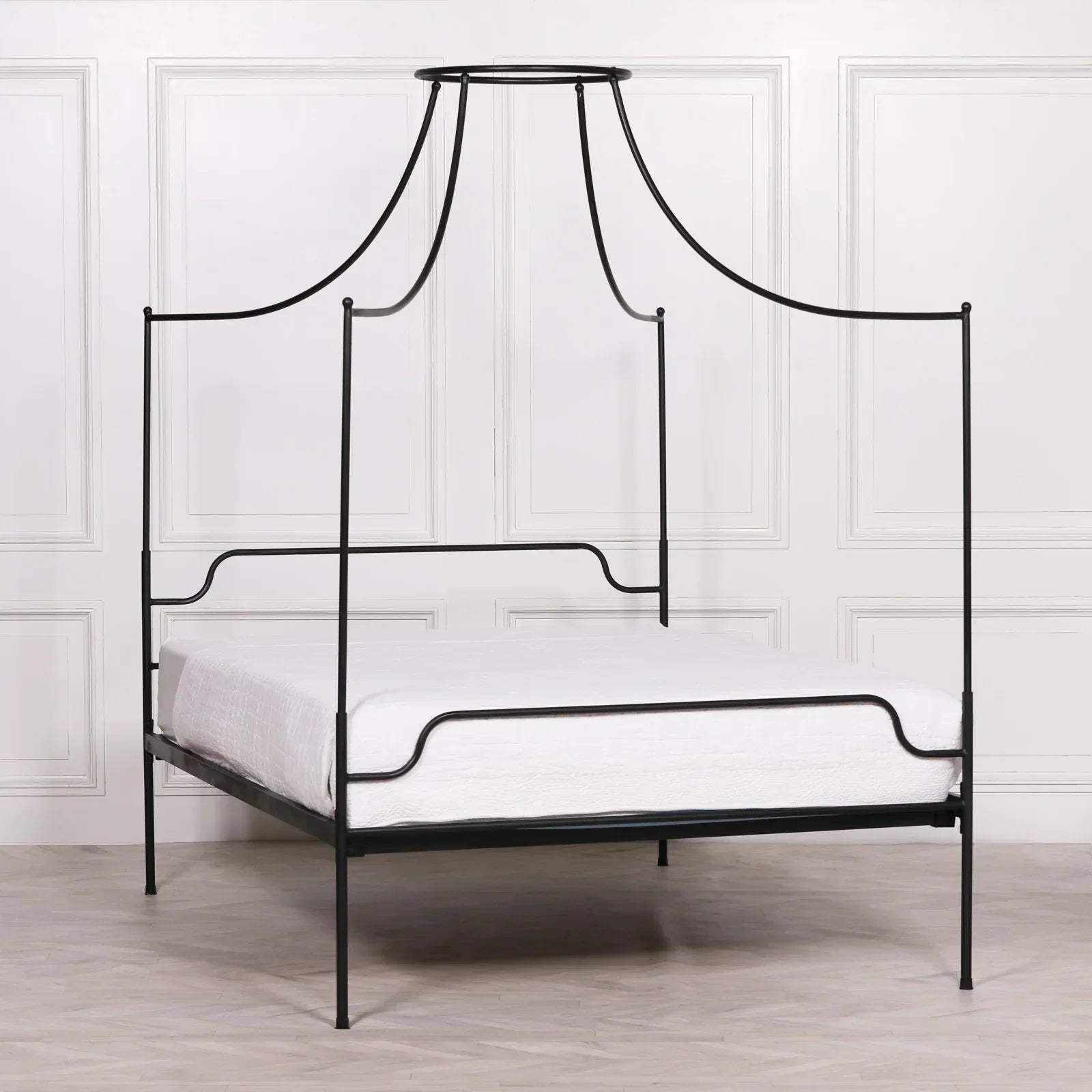 Black metal four poster bed frame with canopy in a minimalist bedroom setting