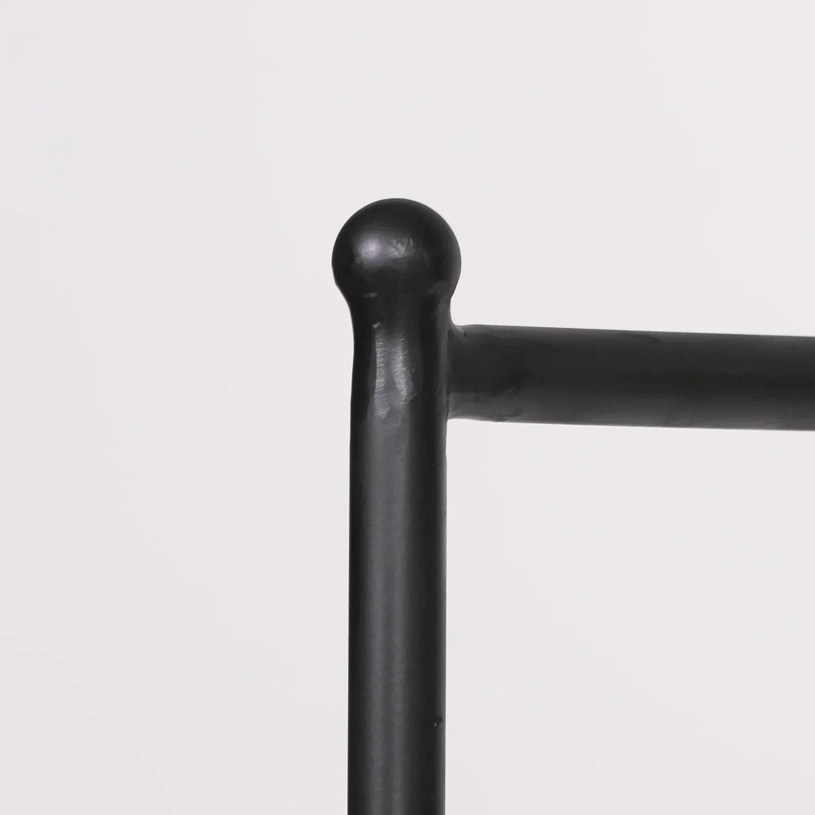 Close-up of black metal bed frame corner with rounded finial