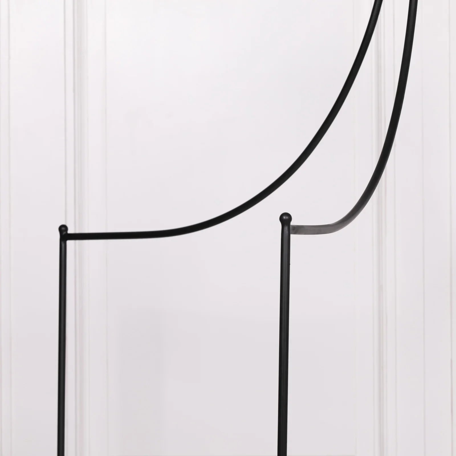 Minimalist black metal chair frame with curved backrest against white wall