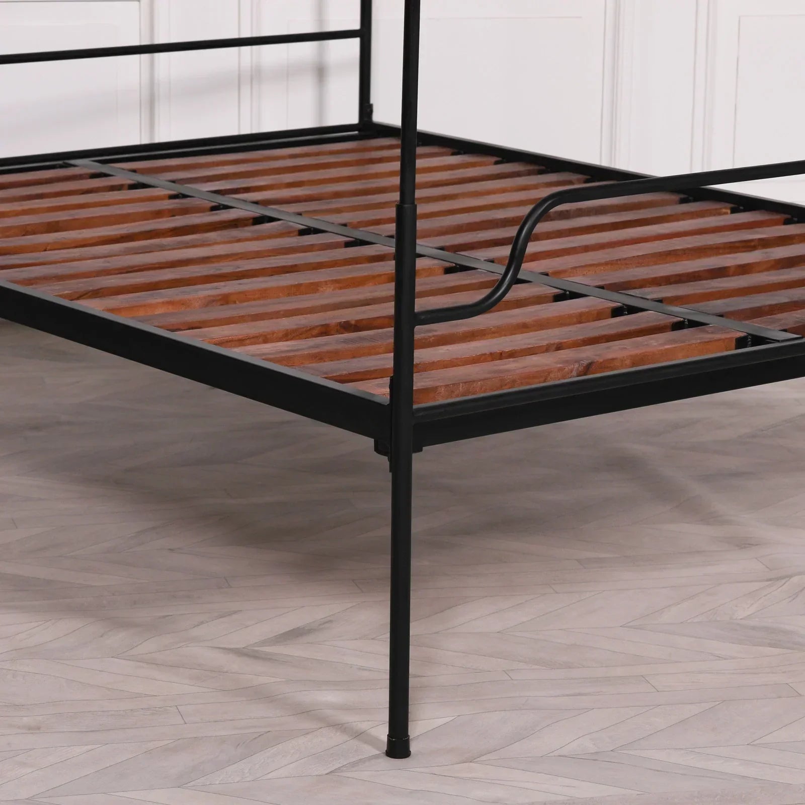 Black metal bed frame with wooden slats, close view of corner and support structure