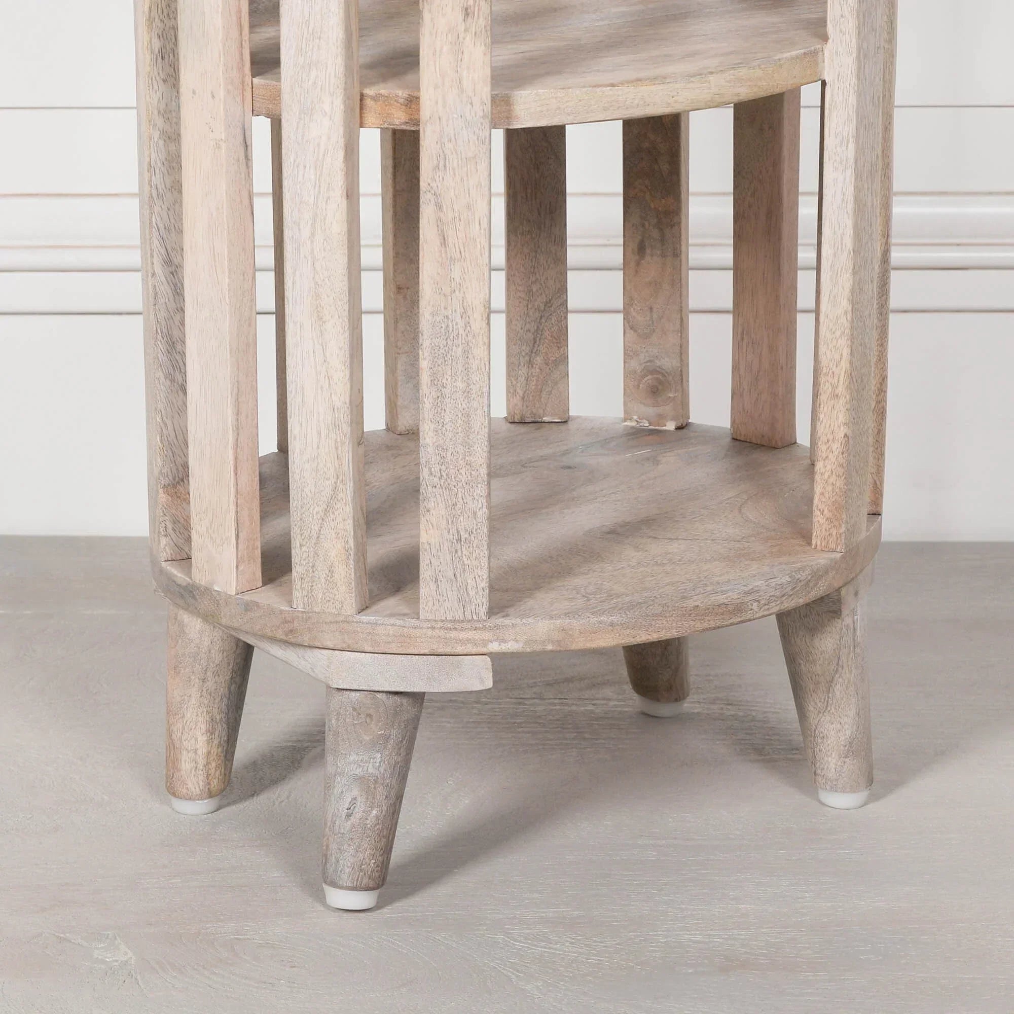 Light wood side table with slatted legs and round lower shelf on wooden floor