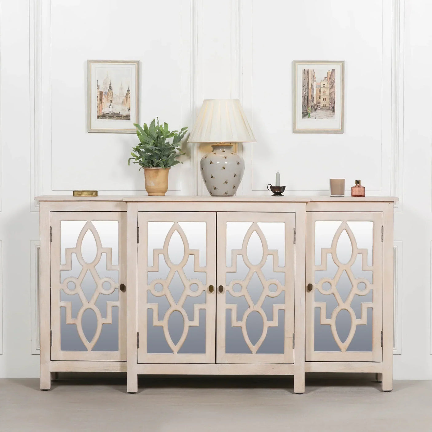 Mirrored sideboard with ornate pattern, four doors, decorative items and wall art above