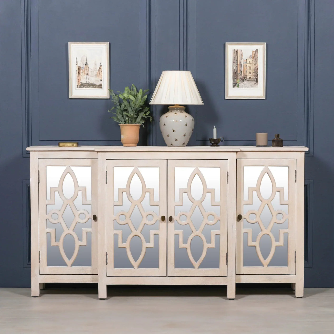 Mirrored sideboard with geometric wood doors, decorative lamp and plant on top