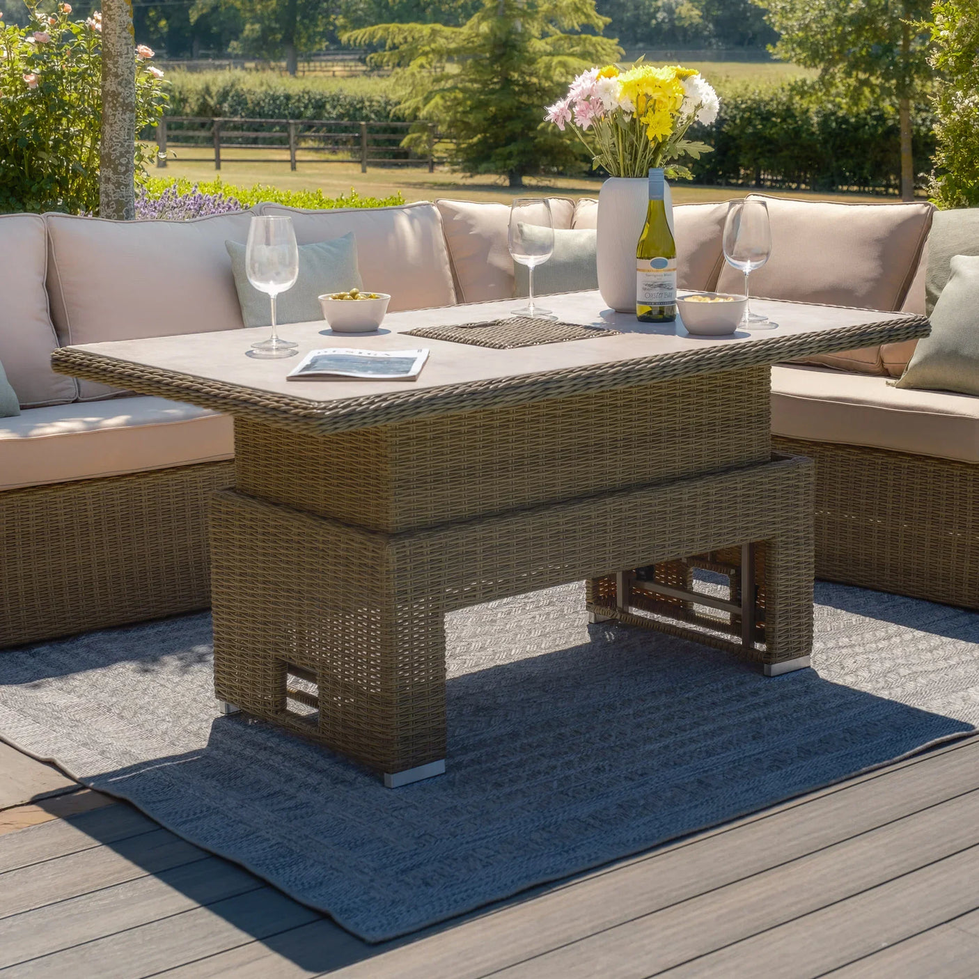 Rattan garden sofa set with cream cushions and glass top table on wooden patio