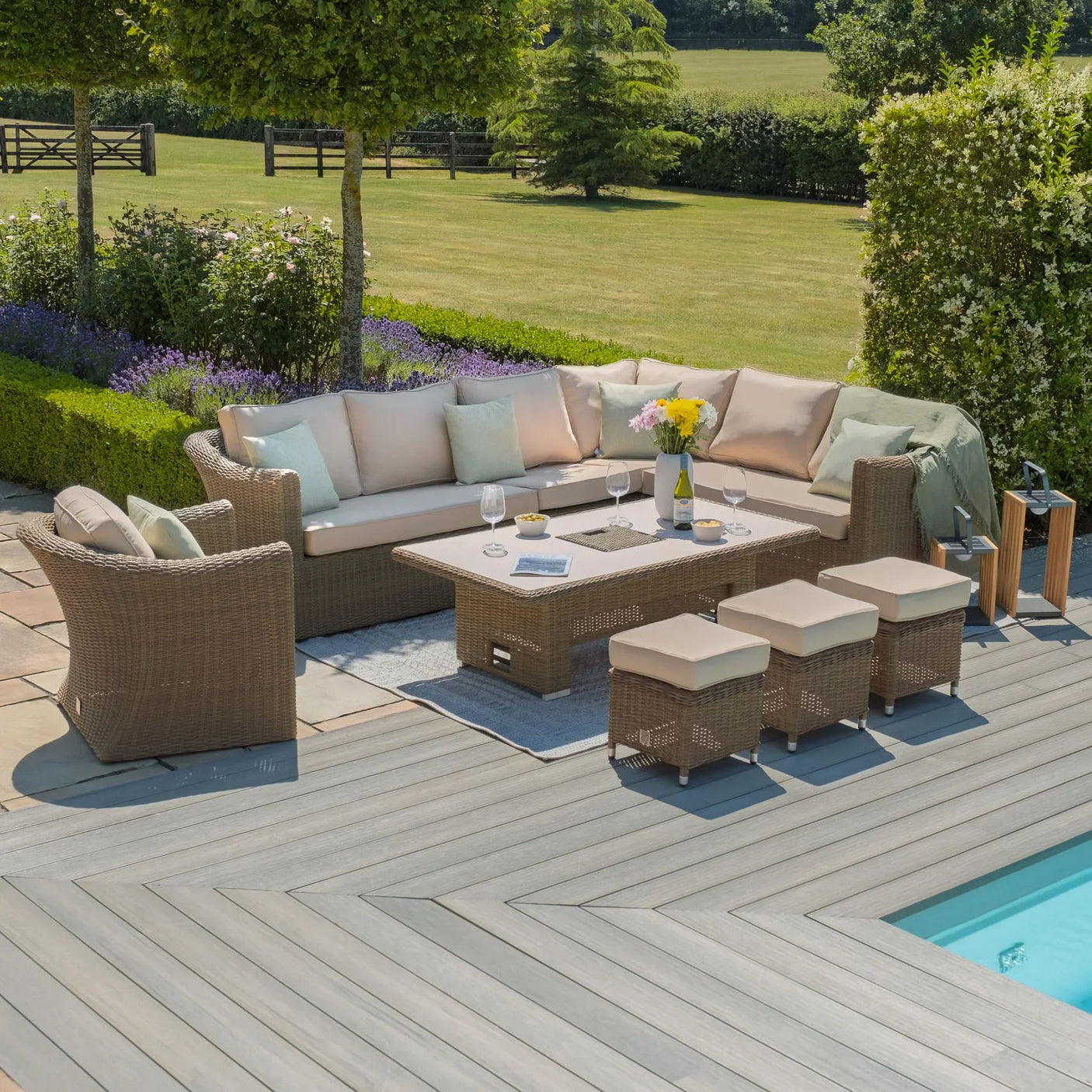 Rattan outdoor corner sofa set with beige cushions, coffee table, stools and garden view