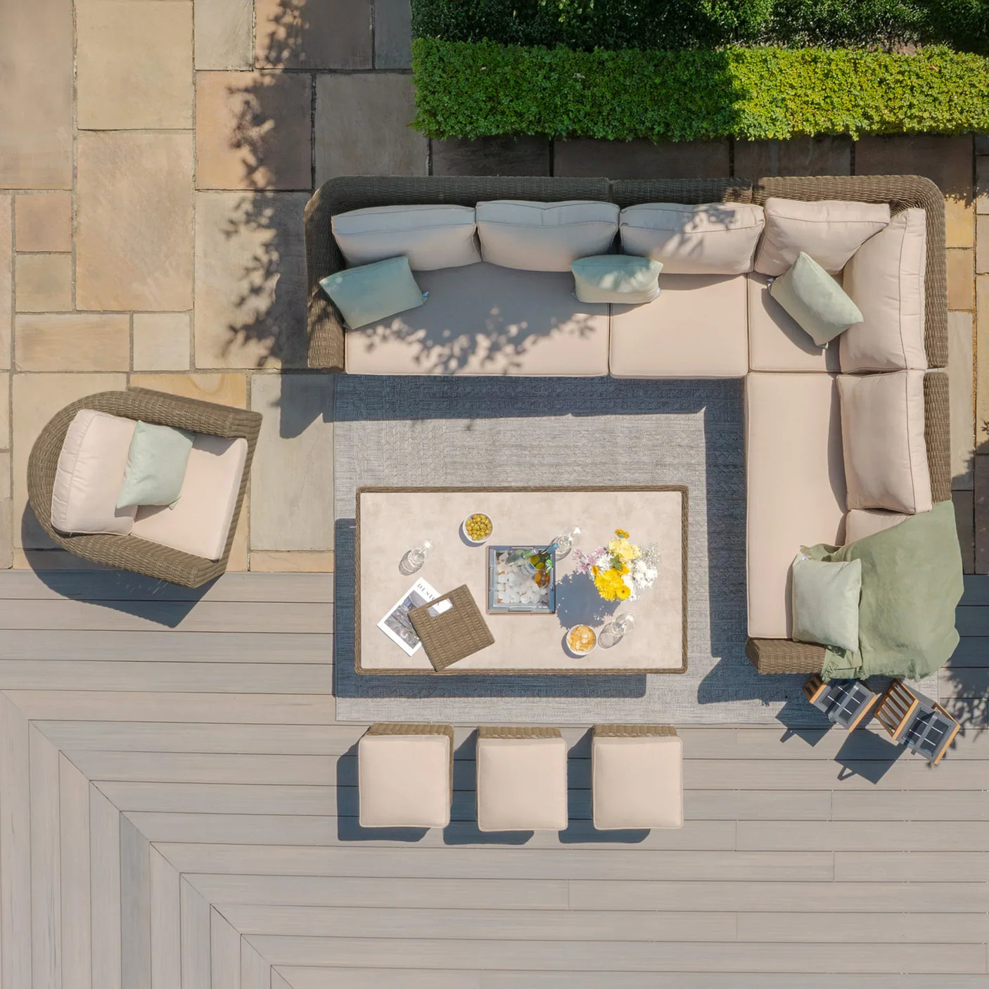 Rattan outdoor corner sofa set with beige cushions, armchair, stools and coffee table on patio