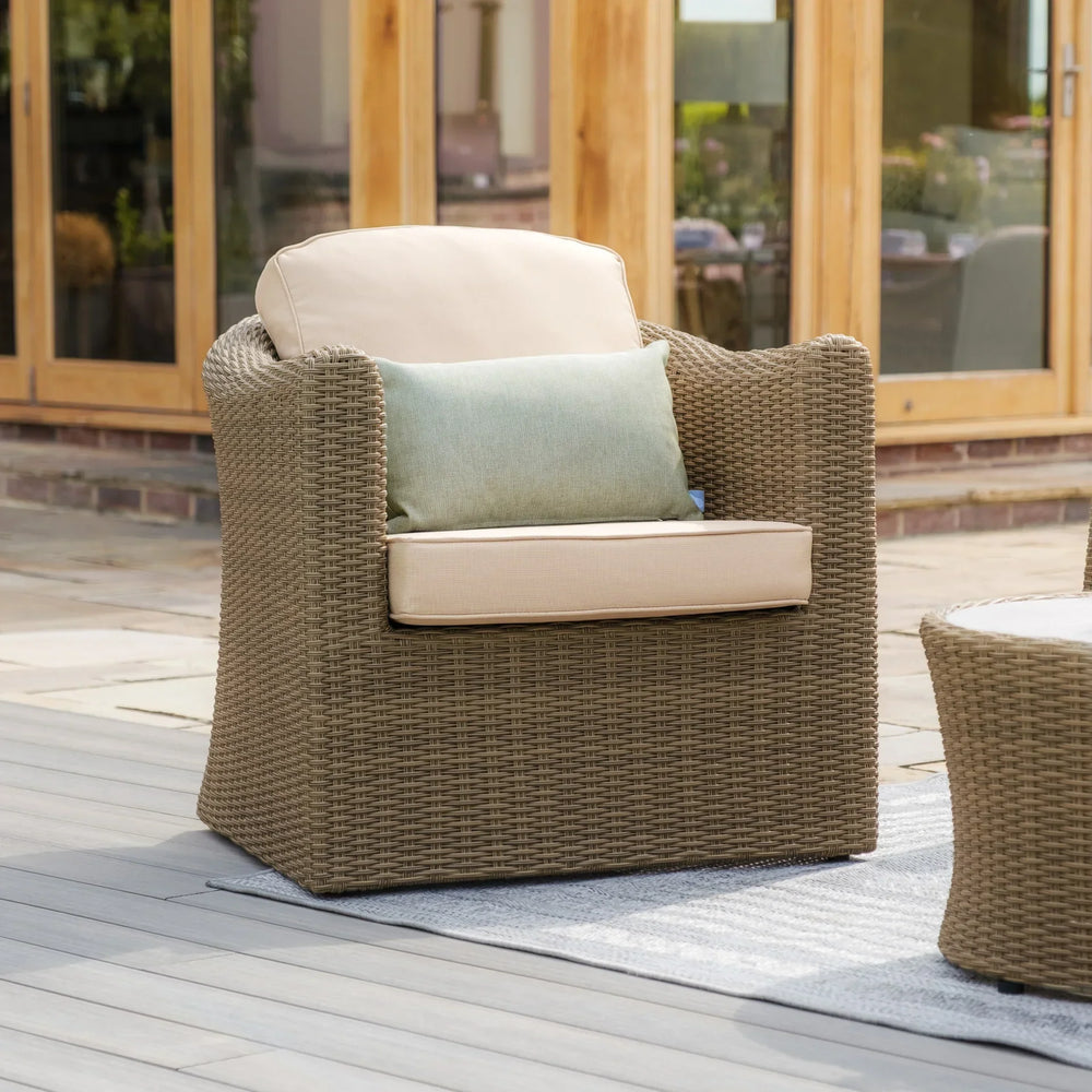 Rattan outdoor armchair with beige cushions and green accent pillow on patio decking