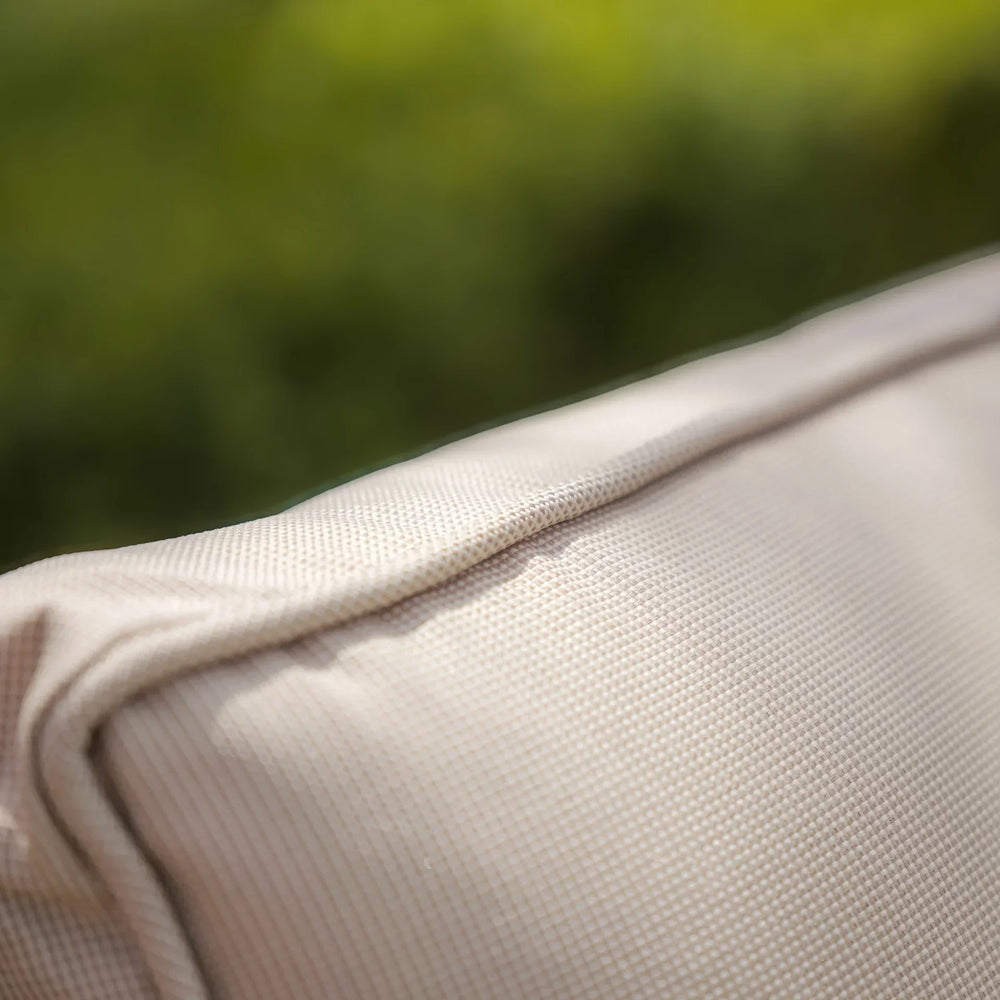 Close up of beige outdoor cushion fabric with textured surface and visible seam