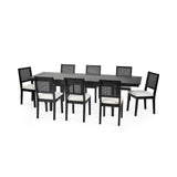 Larger black extending rectangular dining table with eight black chairs with white cushions and woven backrest