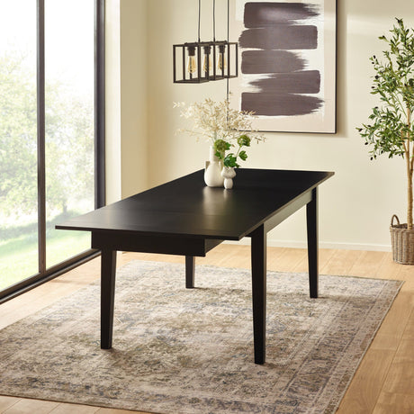 Extending black dining table half extended in bright room with floor plant and modern pendant light
