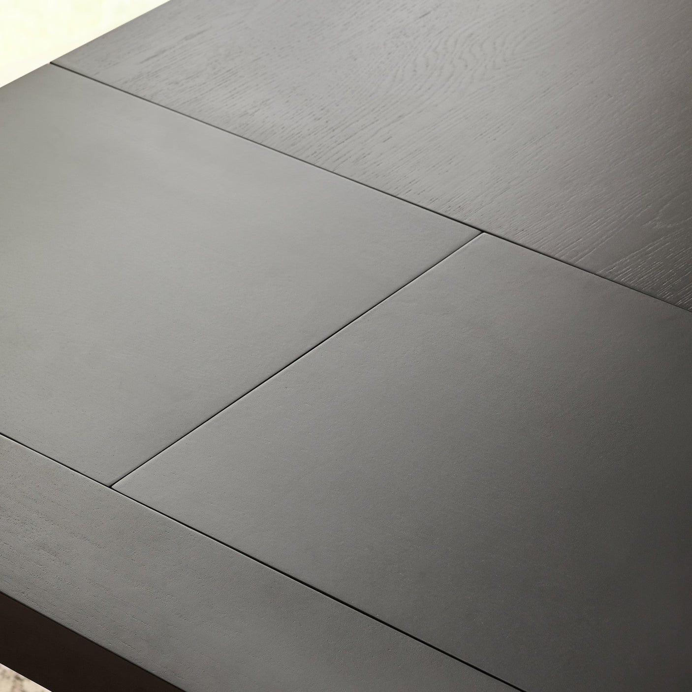 Close-up of extension panel seam on black wooden dining table top revealing wood texture