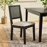 Black wood dining chair with woven cane back and beige upholstered seat in dining room setting.