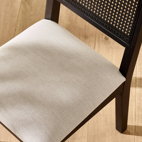 Close-up view of beige fabric upholstered seat with dark wood frame and woven backrest detail